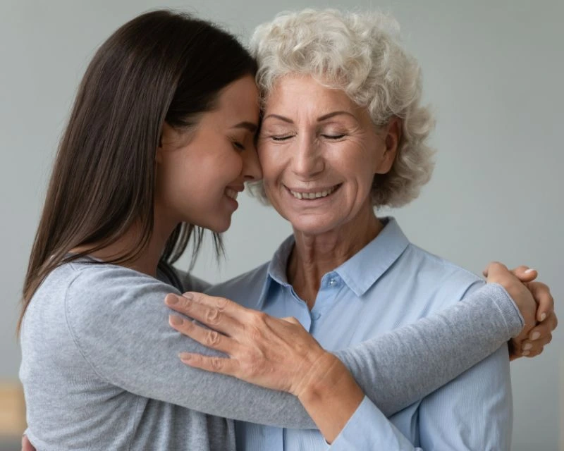 beautiful granddaughter and elderly grandmother cuddling with closed eyes