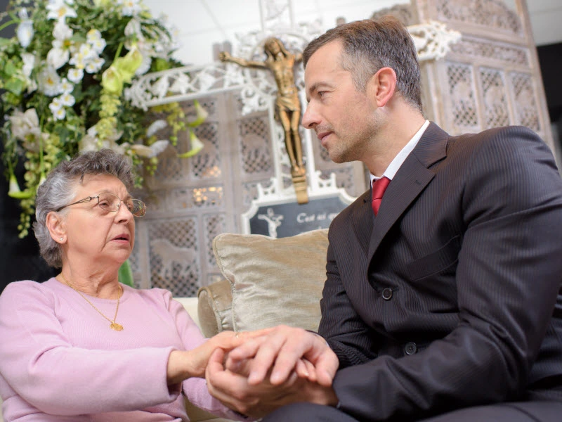 Man in corporate attire comforting a senior lady