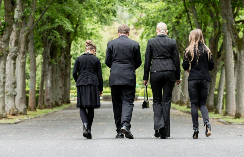 Family wearing black clothes grieving, walking in a cemetery