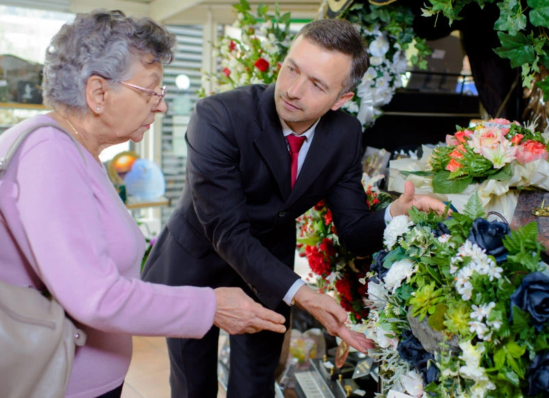 Man in suit helping old woman pick a funeral flowers